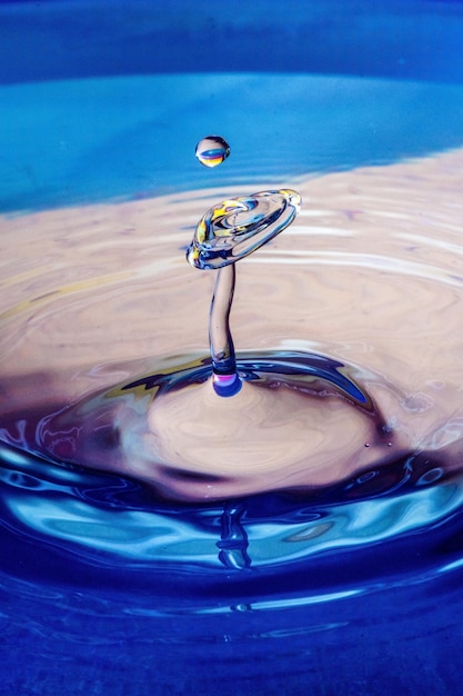 Foto close-up de uma gota caindo em água azul