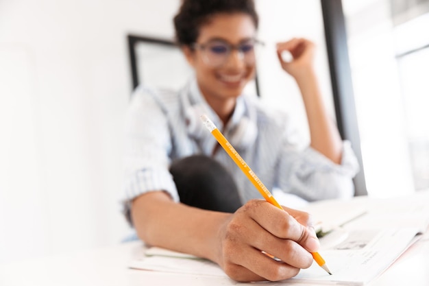 Close-up de uma jovem africana inteligente, estudando enquanto está sentado à mesa em casa