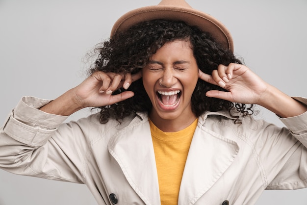 Foto close-up de uma jovem africana sorridente atraente com cabelo encaracolado, vestindo um casaco de outono e um chapéu