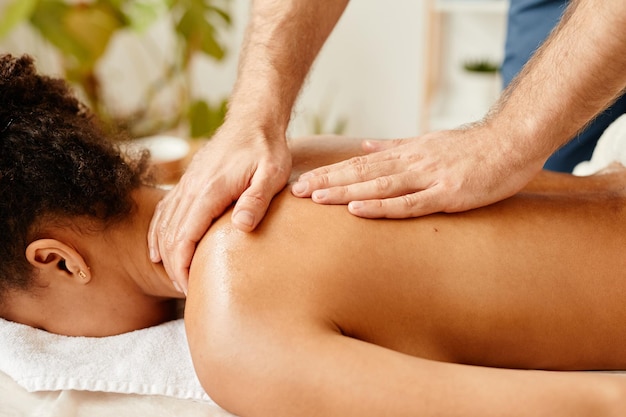 Close-up de uma jovem afro-americana deitada na cama de spa desfrutando do espaço de cópia de massagem nas costas