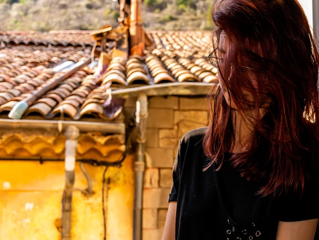 Foto close-up de uma jovem com o cabelo desarranjado de pé perto da casa