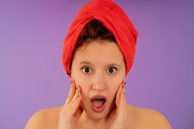 Close-up de uma jovem com uma expressão de choque no rosto enquanto usava uma toalha na cabeça. Conceito de beleza.