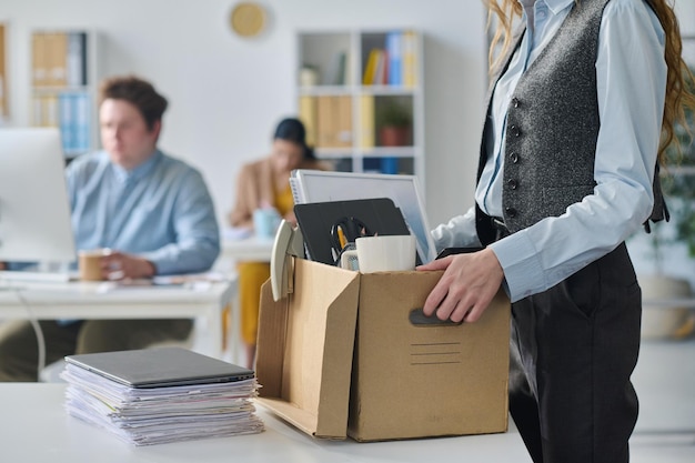 Close-up de uma jovem empresária embalando suas coisas em seu local de trabalho durante a mudança para um novo escritório