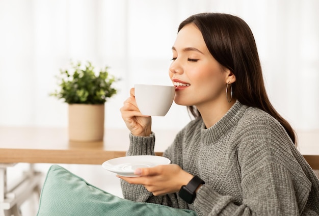 Close-up de uma jovem feliz bebendo café em casa