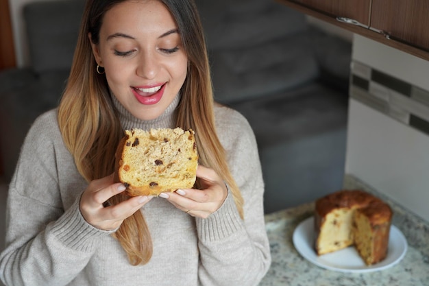 Foto close-up de uma jovem feliz comendo uma fatia de panettone tradicional bolo de natal