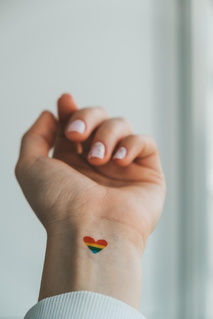 Foto close-up de uma jovem hippie caucasiana com uma bandeira arco-íris em forma de coração pintada