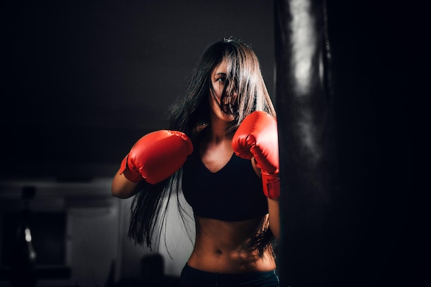 Close-up de uma jovem mulher a boxear na sala escura.