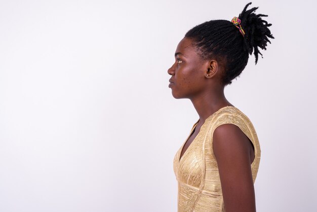 Close-up de uma jovem mulher africana com um vestido dourado pronto para a festa, isolada