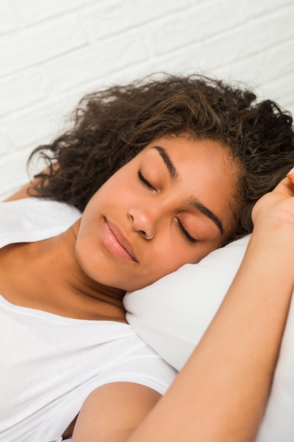 Foto close-up de uma jovem mulher afro-americana cansada, dormindo na cama