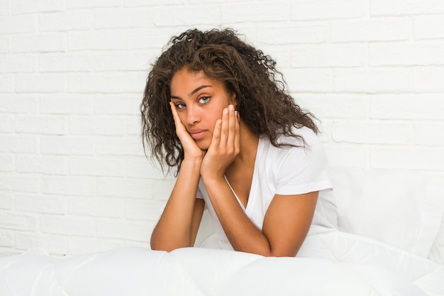 Close-up de uma jovem mulher afro-americana cansada, sentada na cama