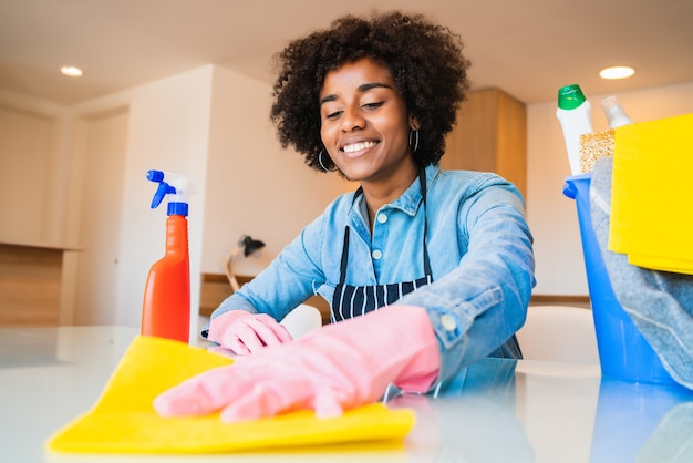 Foto close-up de uma jovem mulher afro fazendo limpeza na nova casa