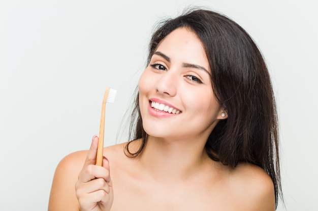 Close-up de uma jovem mulher hispânica bonita e natural, segurando uma escova de dentes