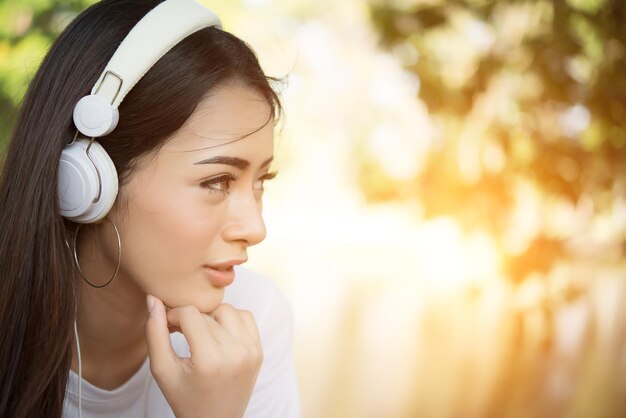 Foto close-up de uma jovem ouvindo música através de fones de ouvido