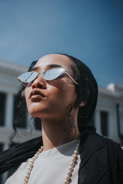 Close-up de uma jovem usando óculos de sol contra o céu azul