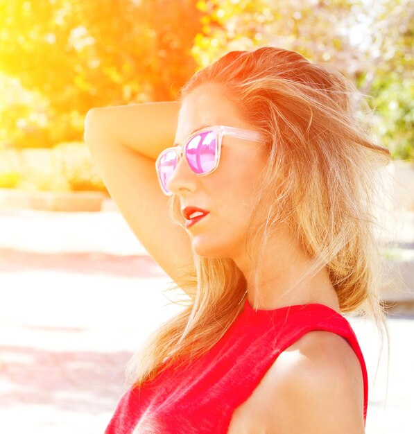 Foto close-up de uma jovem usando óculos de sol durante um dia ensolarado