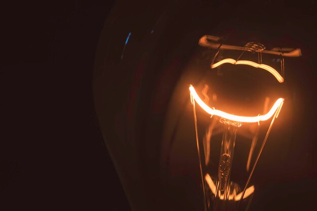 Foto close-up de uma lâmpada iluminada em uma sala escura