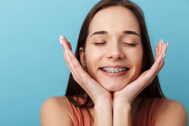 Close-up de uma linda garota jovem, isolada sobre uma parede azul, fazendo uma careta