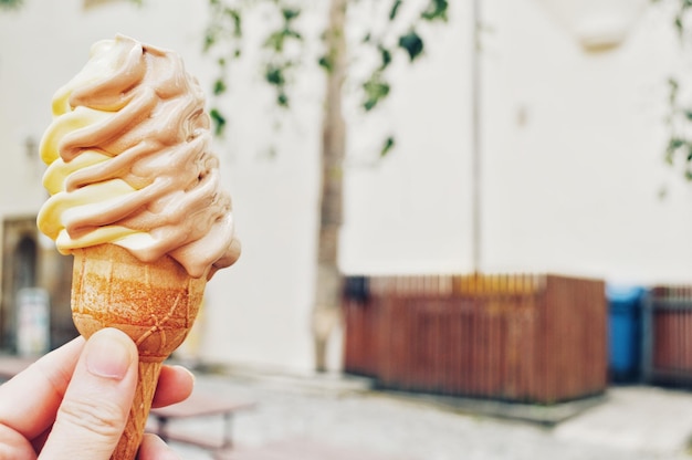 Foto close-up de uma mão segurando um cone de sorvete