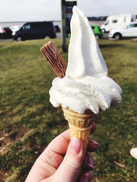 Foto close-up de uma mão segurando um cone de sorvete