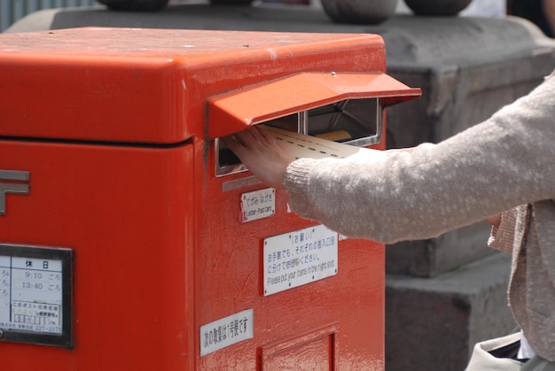 Foto close-up de uma mão segurando uma caixa de correio vermelha