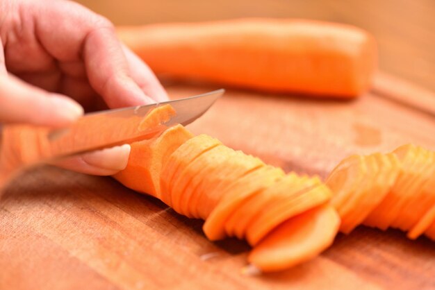 Foto close-up de uma mão segurando uma folha de laranja na tábua de cortar