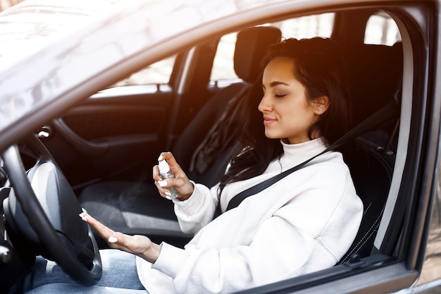 Close-up de uma mão. Uma mulher usa um desinfetante para as mãos em um carro. Protege contra vírus e bactérias. O modelo feminino não quer a doença no coronavírus covid-19