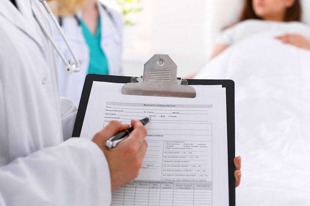 Close-up de uma médica ao preencher o registro do histórico médico.
