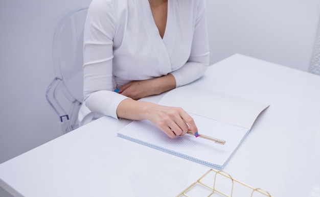 close-up de uma médica fazendo anotações em um caderno em uma mesa