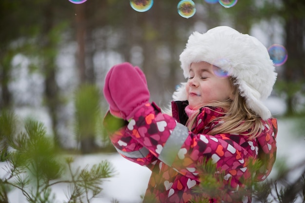Close-up de uma menina com bolhas de sabão no inverno