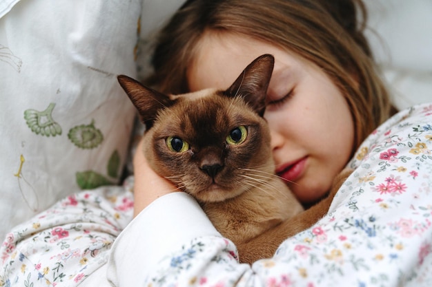 Close-up de uma menina dormindo com um gato birmanês