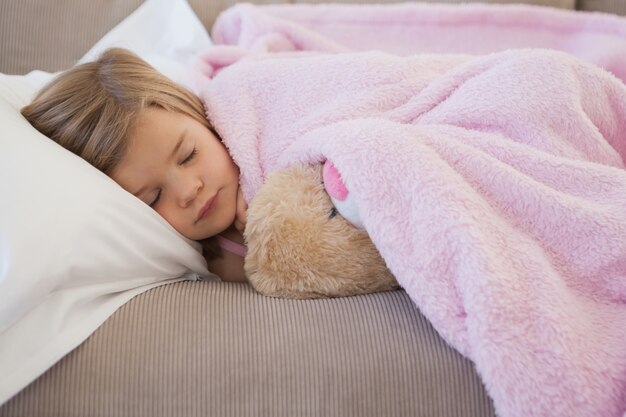 Foto close-up de uma menina dormindo no sofá com brinquedo recheado