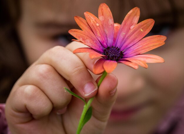 Foto close-up de uma menina segurando uma flor