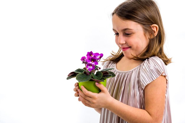 Foto close-up de uma menina sorridente com um vaso de flores de pé contra um fundo branco