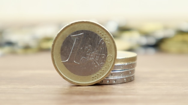 Close-up de uma moeda de euro na área de trabalho. O dinheiro metálico europeu e, no fundo, as moedas de cêntimos de euro estão desfocados.