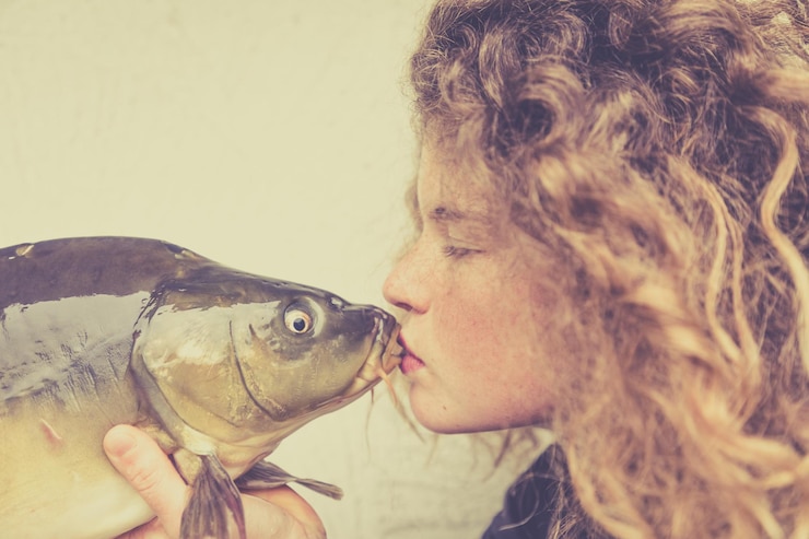 Foto close-up de uma mulher a beijar um peixe