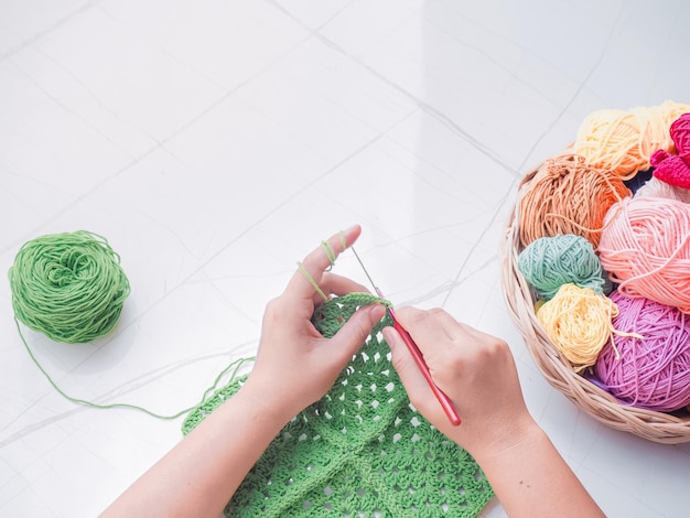 Close-up de uma mulher a tricotar com lã verde