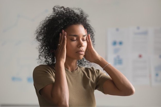 Foto close-up de uma mulher afro-americana exausta sente-se mal, toque nos templos de massagem sofrem de dor de cabeça, trabalhadora negra cansada tem enxaqueca ou tontura com os olhos fechados conceito de problema de saúde