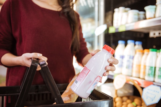 Foto close-up de uma mulher com uma cesta de compras de produtos lácteos em uma mercearia