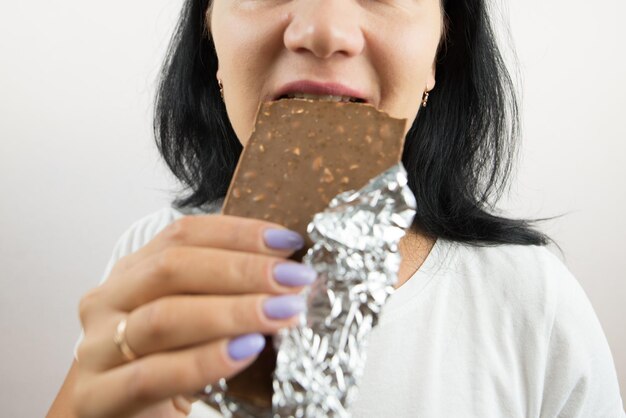 Close-up de uma mulher comendo uma barra de chocolate