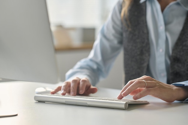 Close-up de uma mulher de escritório digitando no teclado enquanto trabalha no computador em seu local de trabalho