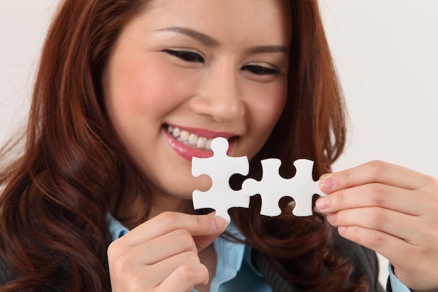 Foto close-up de uma mulher de negócios sorridente segurando peças de quebra-cabeça contra um fundo branco