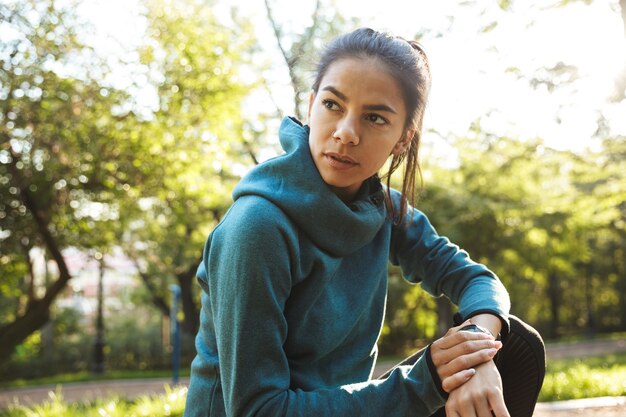 Close-up de uma mulher jovem e atraente fitness vestindo roupas esportivas, fazendo exercícios ao ar livre, usando smartwatch