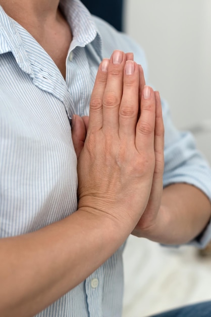 Close-up de uma mulher milenar pacífica meditando saúde mental Mulher segurando as mãos em um gesto de namaste meditando equilíbrio mental tempo para si mesma Alívio do estresse mediação conceito de plenitude da mente