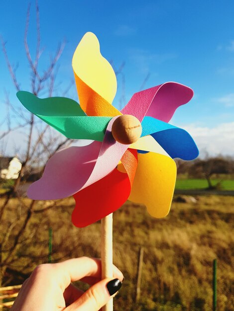 Foto close-up de uma mulher segurando um brinquedo de roda giratória no campo contra o céu