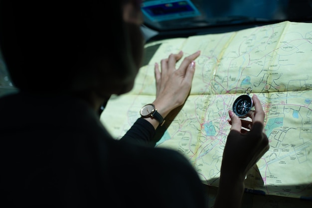 Foto close-up de uma mulher segurando uma bússola de navegação sobre o mapa