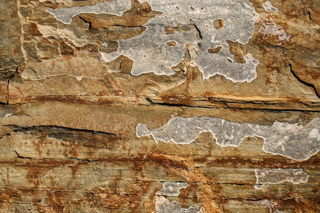 Close-up de uma parede de ardósia de montanha marrom-rufous camadas com manchas desiguais.