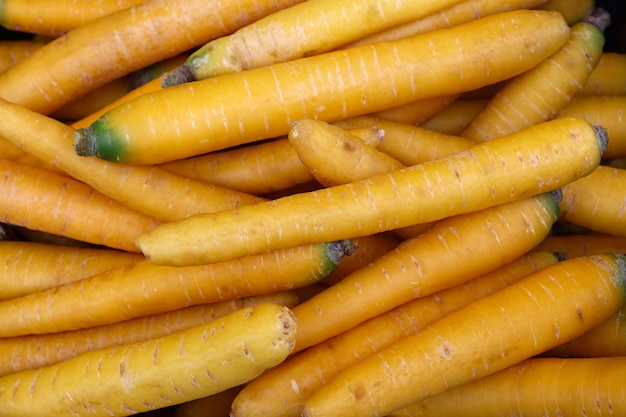 Close-up de uma pilha de cenouras amarelas asiáticas frescas da primavera em exibição de varejo, vista de alto ângulo