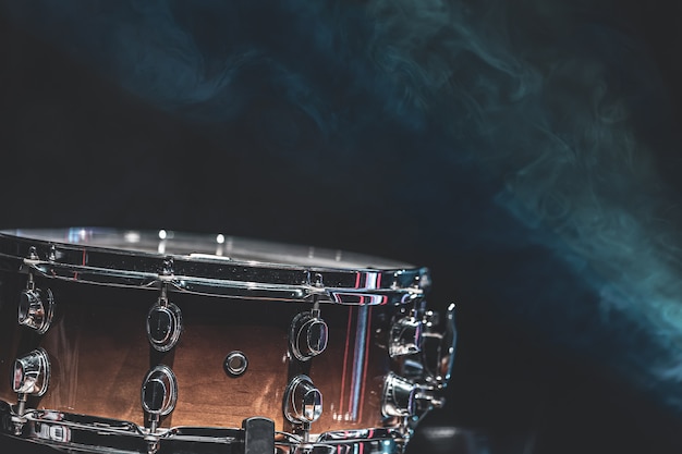 Close-up de uma tarola, instrumento de percussão em um fundo escuro com neblina, bela iluminação.