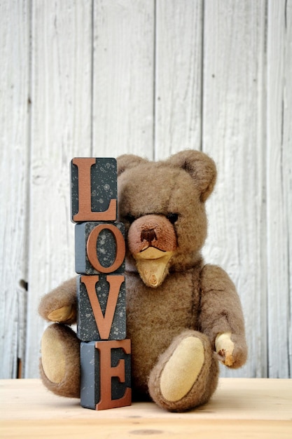 Foto close-up de ursinho de pelúcia com blocos de amor em mesa de madeira