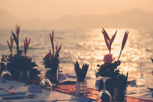 Foto close-up de vaso na mesa contra o mar durante o pôr-do-sol